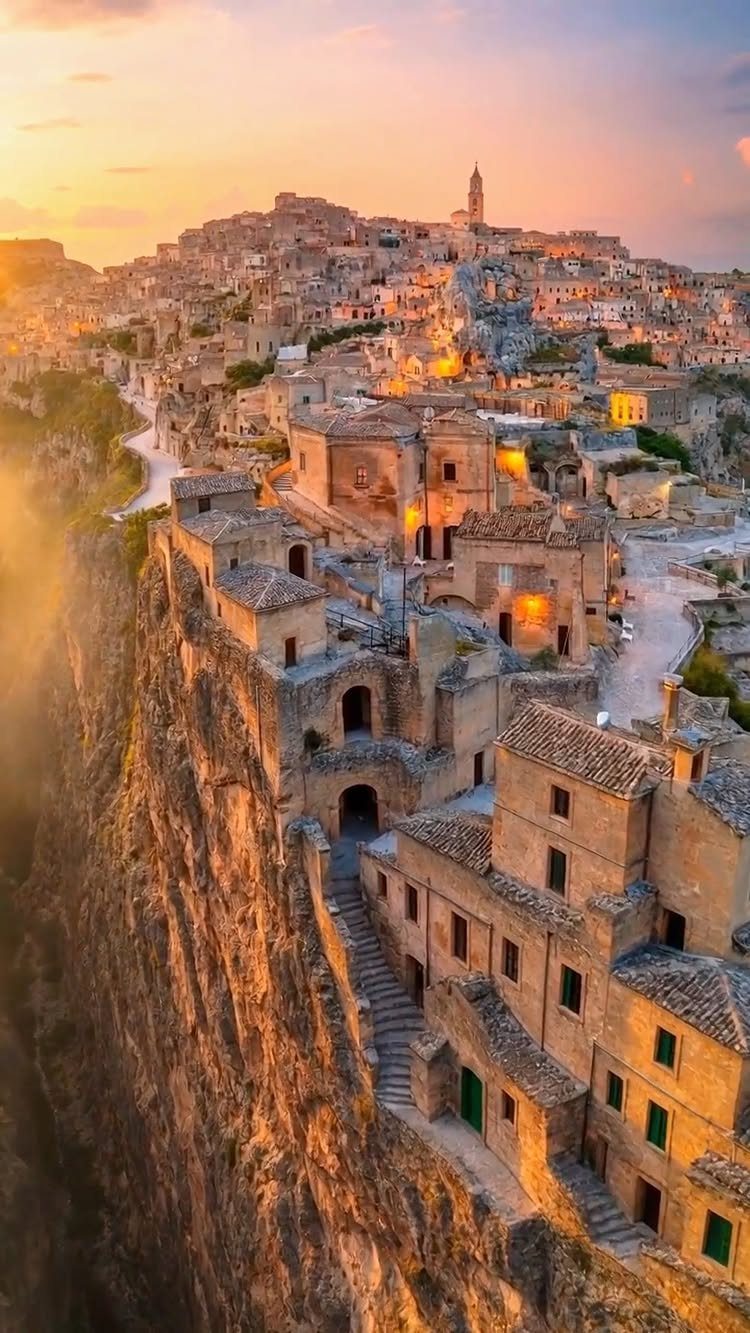 13 Pretty Places in Italy Worth Visiting in 2026 13 Ancient stone cave dwellings carved into a rocky cliffside during a golden sunset.