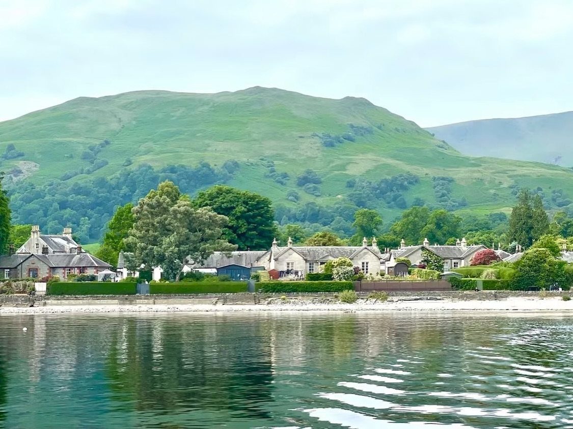 Lakeside village with stone houses and rolling green hills in Scotland