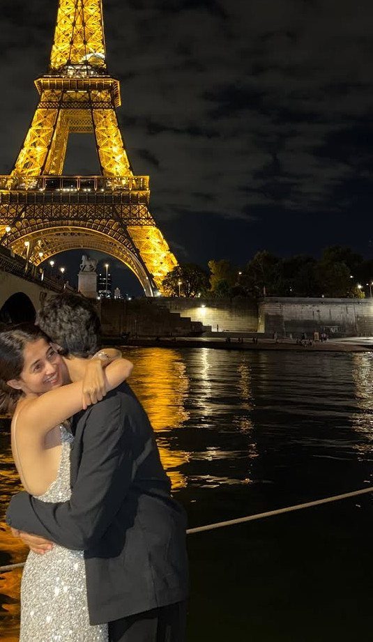 Couple embracing by the river with the illuminated Eiffel Tower in the background