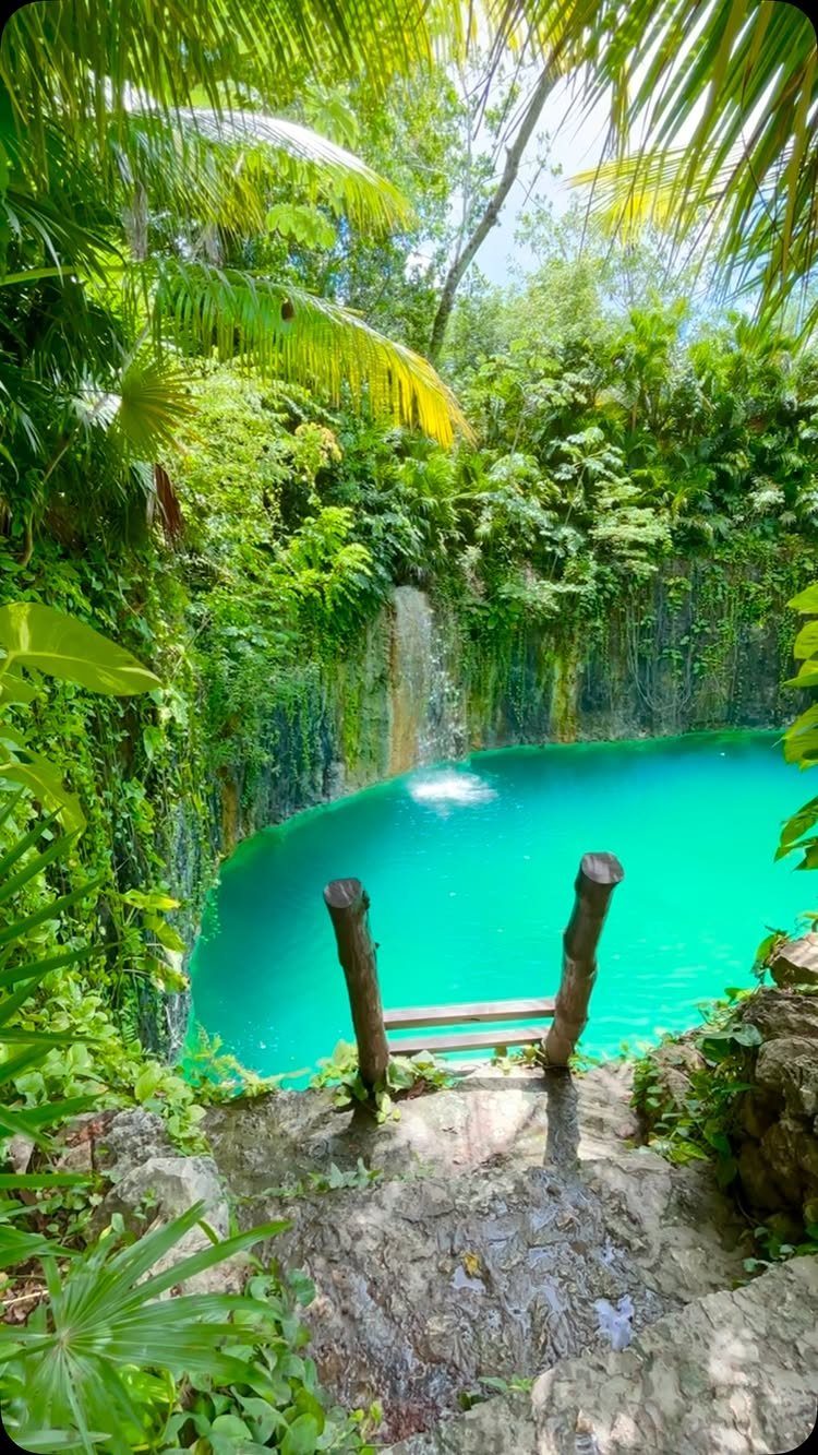 Turquoise blue lagoon surrounded by lush tropical greenery and a small waterfall.