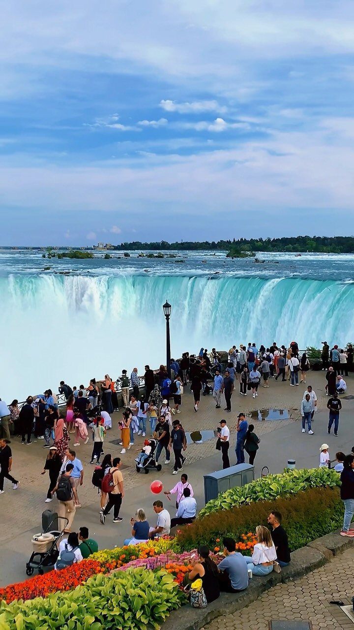 7 Sights to See in the US, From Acadia to Old Idaho 4 Niagara Falls cascading over a cliff with tourists watching from a paved overlook.