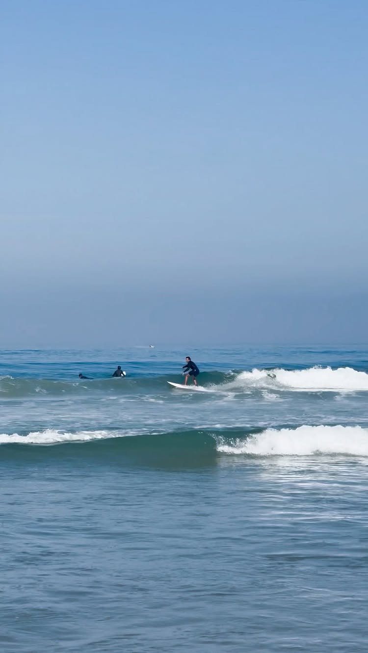 Surfer riding a white surfboard on a breaking blue ocean wave.