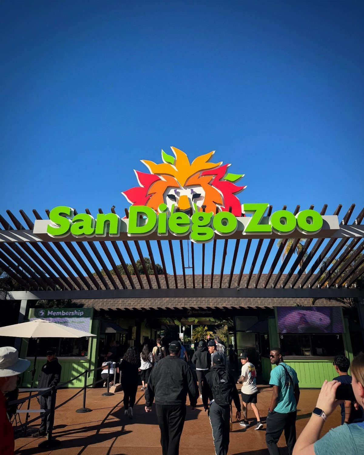 San Diego Zoo entrance sign with a colorful lion under a blue sky.