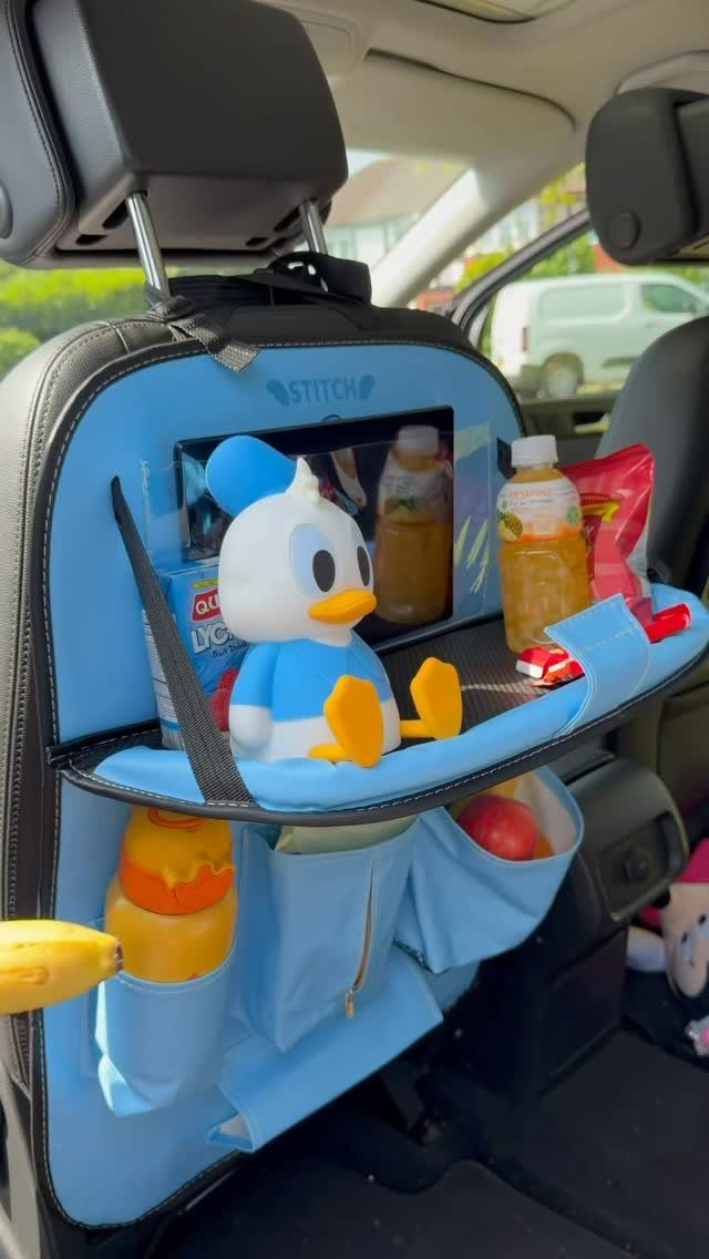 Blue car seat organizer filled with snacks, drinks, and a Donald Duck plush.