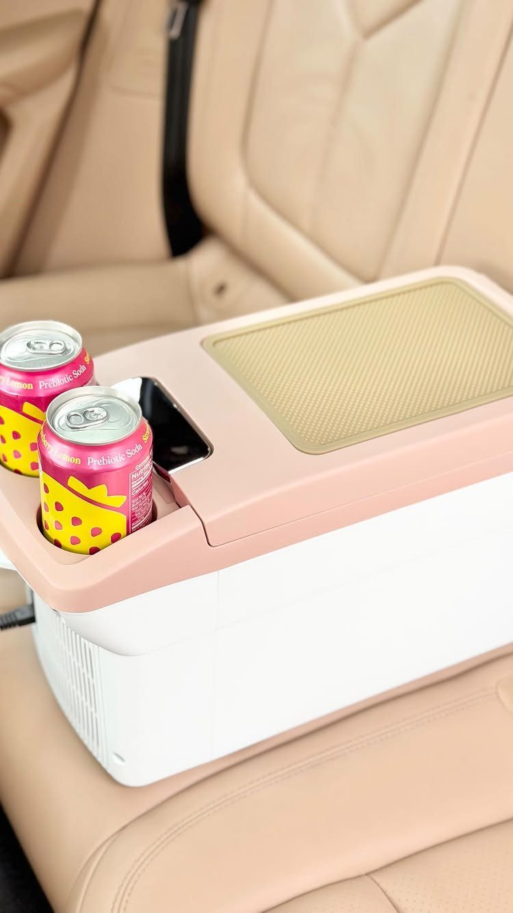 White and pink portable car cooler with drinks on a tan leather seat