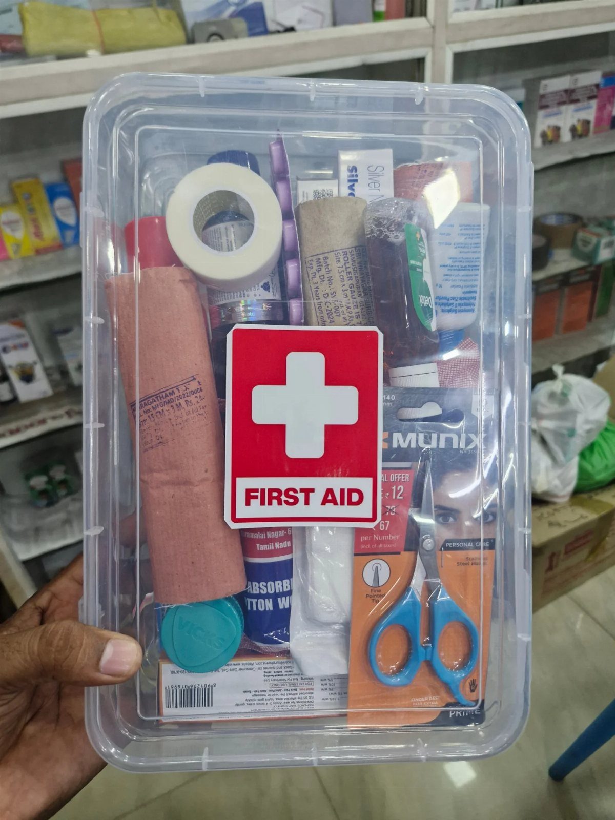 First aid kit in a clear plastic box with bandages and scissors.