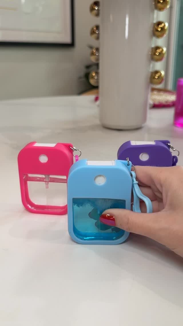 Hand holding a small blue portable hand sanitizer dispenser on a white table