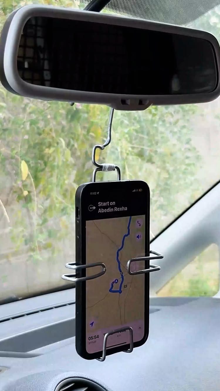 Smartphone with map navigation held by a wire mount on a rearview mirror