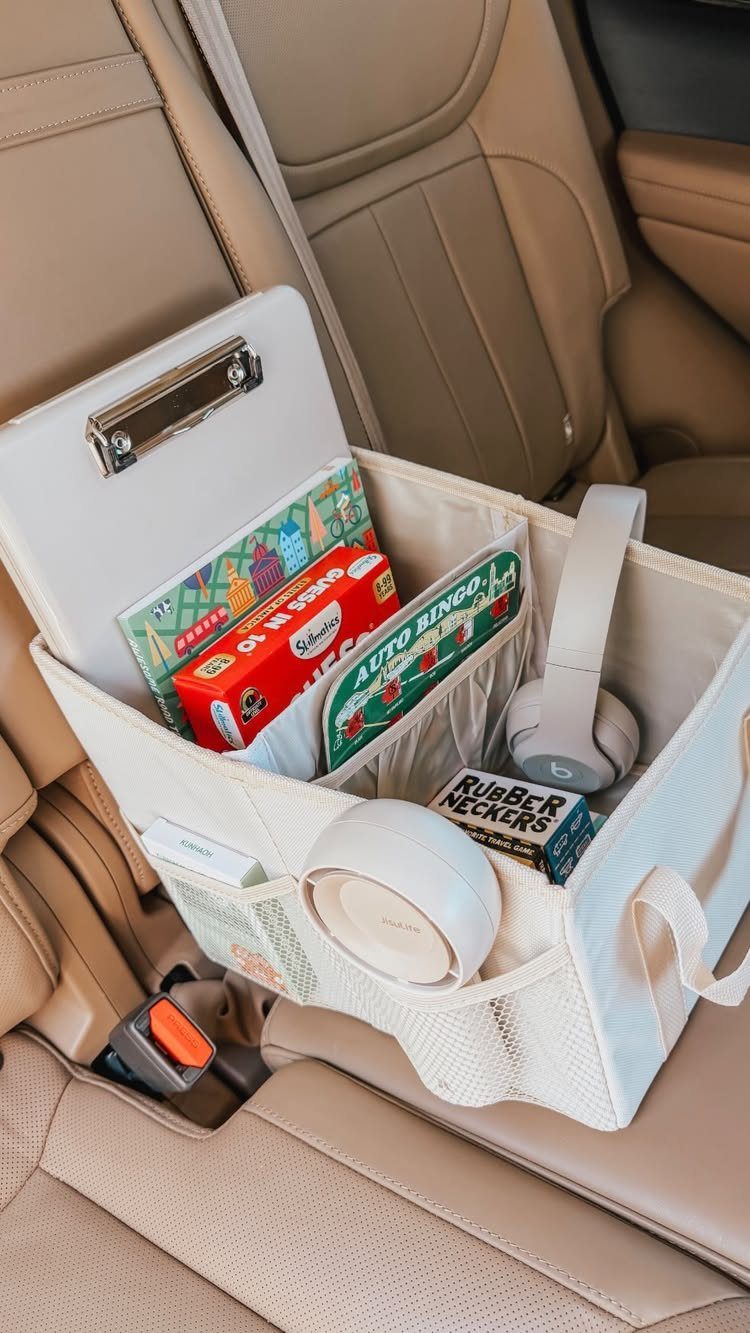 White car seat organizer filled with travel games, headphones, and a clipboard.