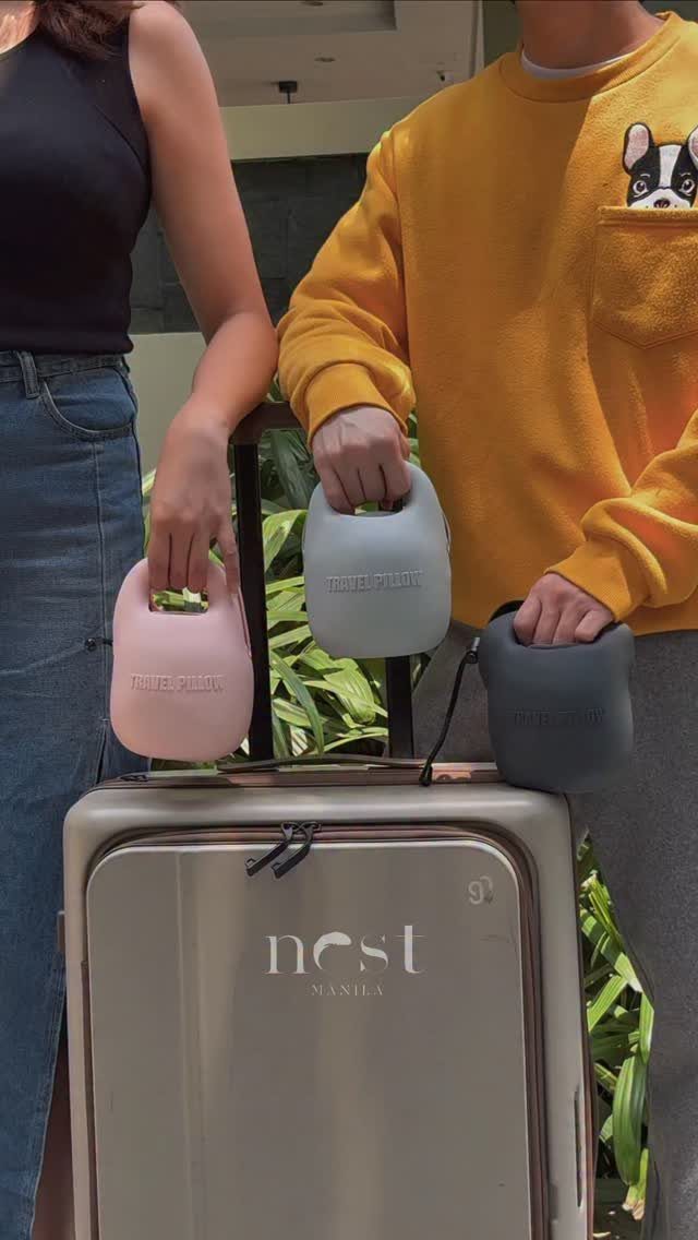 Three memory foam travel pillows in different colors held next to a suitcase.