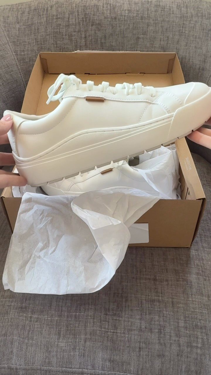 Things to Pack for NYC: 7 Easy Items for Any Trip 5 White platform sneakers in a brown shoebox resting on a grey fabric sofa.