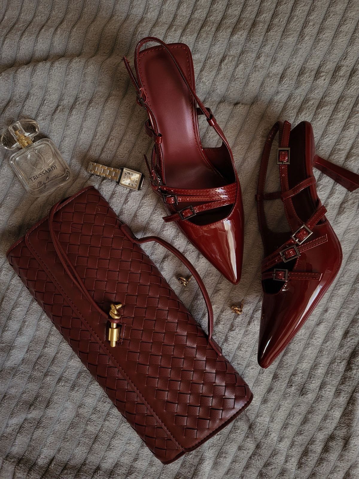 Things to Pack for NYC: 7 Easy Items for Any Trip 3 Red patent leather high heels and matching woven clutch on grey fabric.