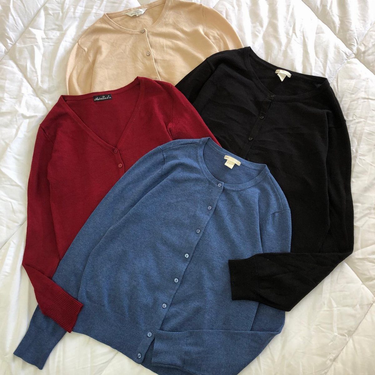 Things to Pack for NYC: 7 Easy Items for Any Trip 2 Three button-up cardigans in beige, red, and blue on a white quilted background.