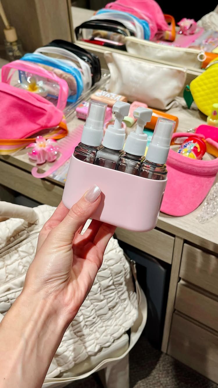Things to Pack for NYC: 7 Easy Items for Any Trip 4 Hand holding a pink travel holder with four small clear spray bottles.