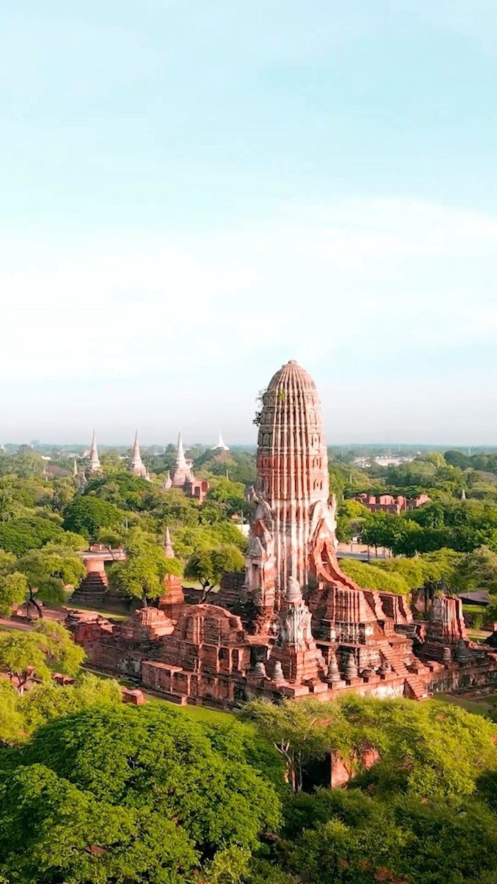 Ancient brick prang tower and stupas surrounded by green trees in Ayutthaya