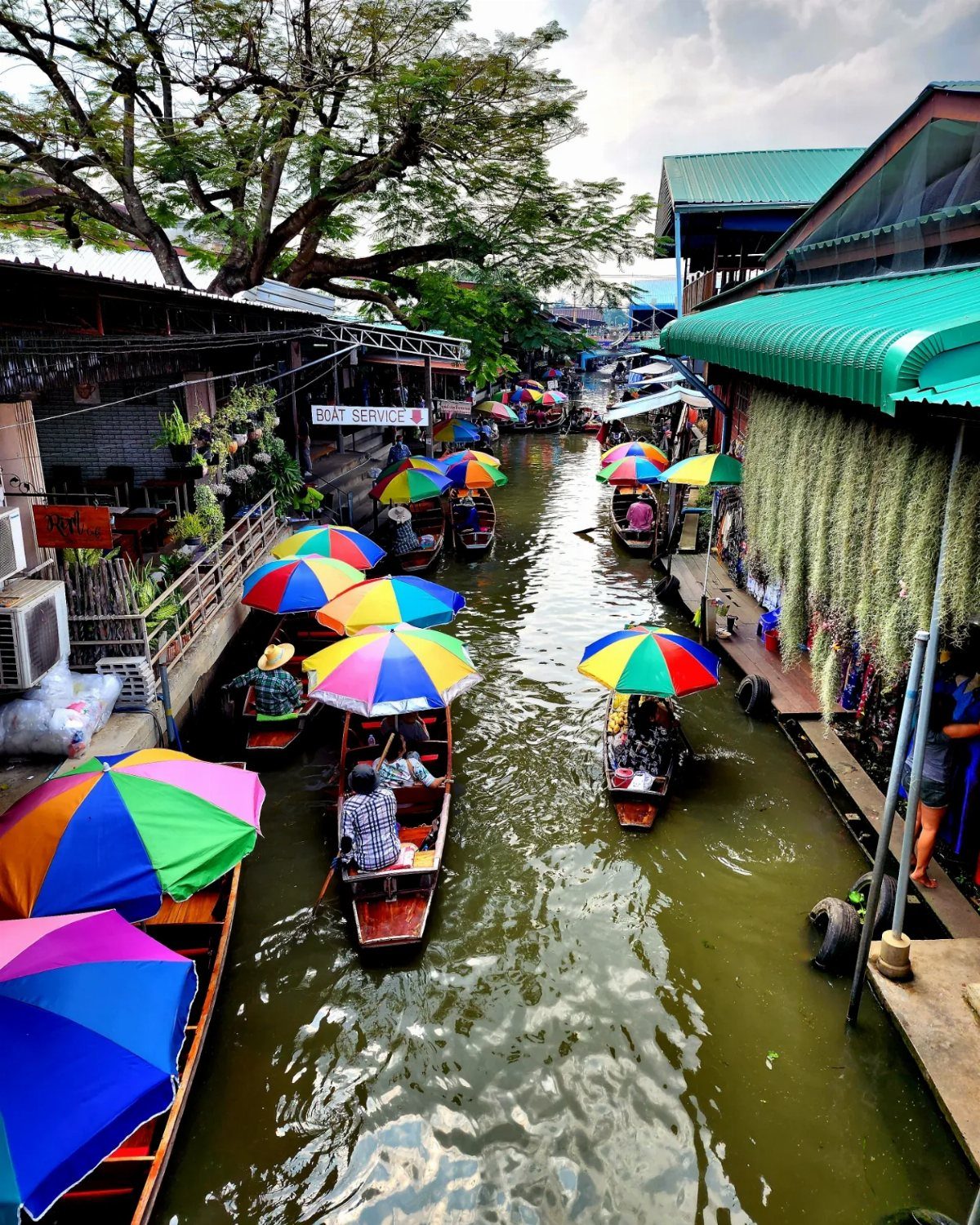 Wooden boats with colorful umbrellas floating down a narrow canal in a market