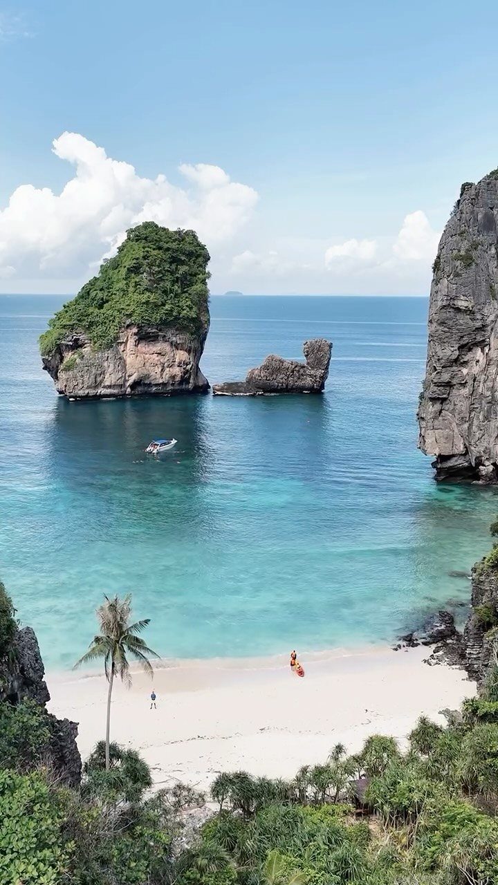 Turquoise water and white sand beach surrounded by towering limestone cliffs in Krabi.