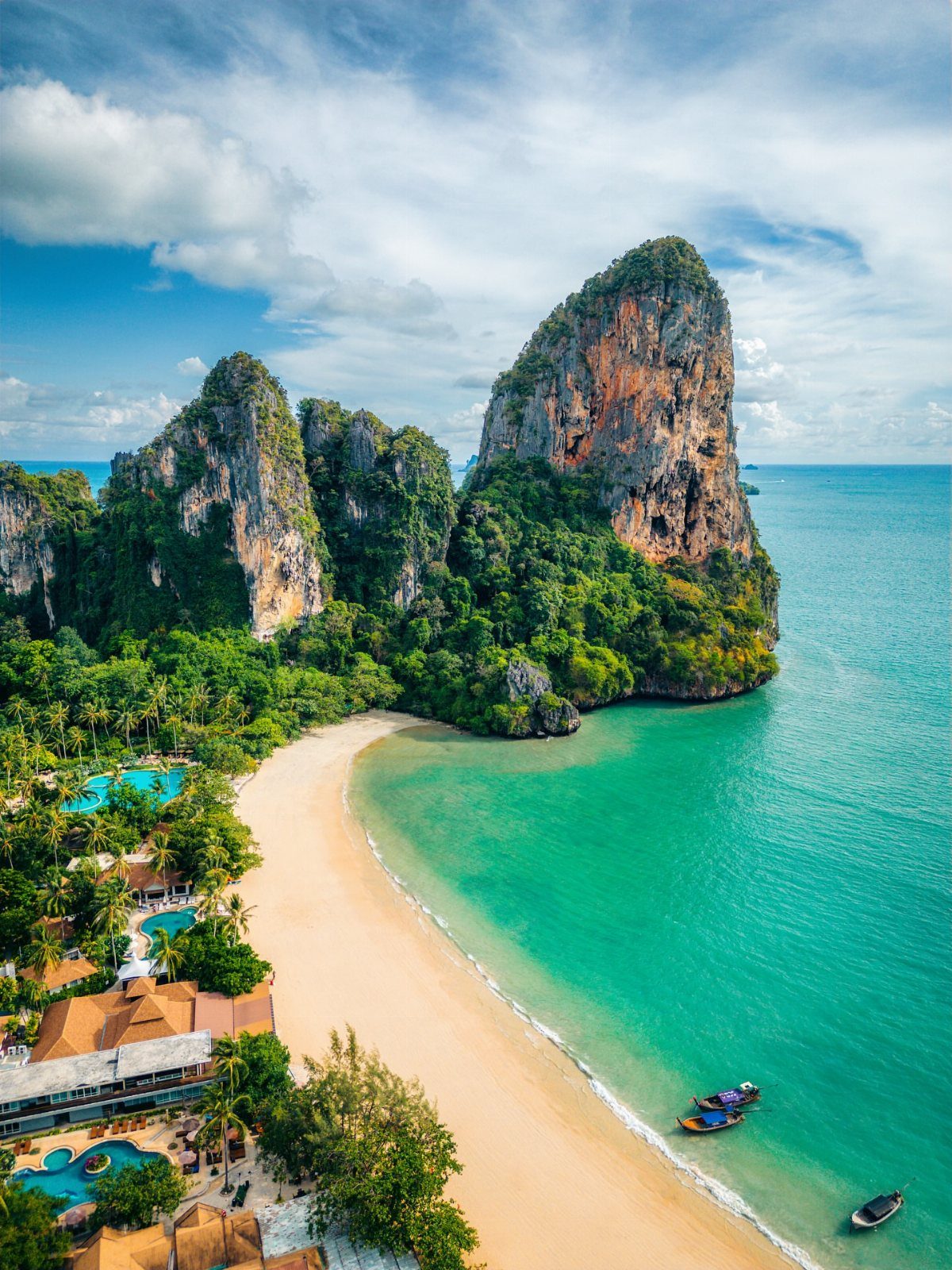 White sand beach and turquoise water surrounded by towering limestone cliffs in Thailand