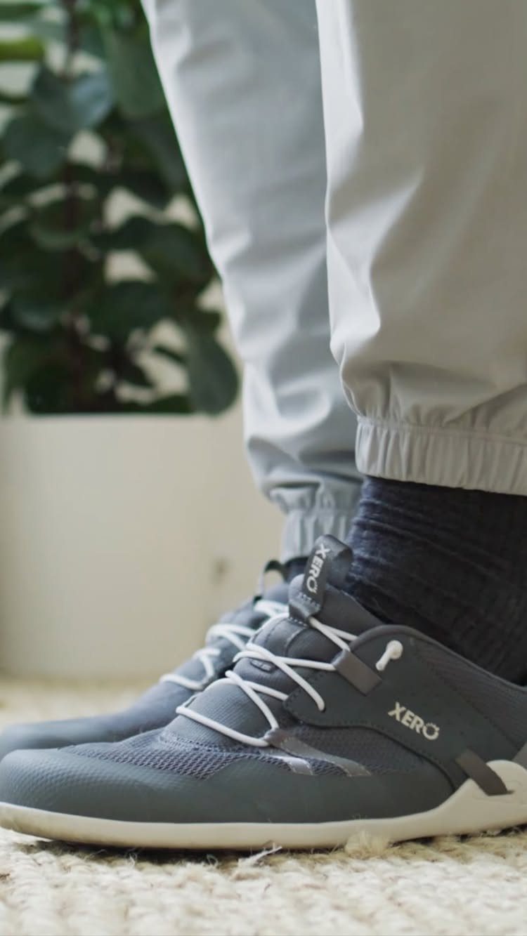 Travel Necessities for Japan: 10 Items Worth Packing 1 Grey athletic sneakers with white laces worn with light grey trousers on carpet.