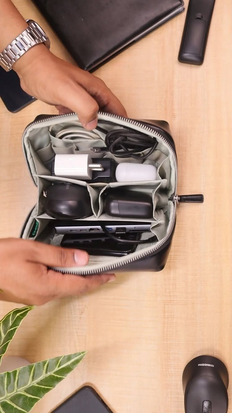 Travel Necessities for Japan: 10 Items Worth Packing 9 Small black electronic organizer pouch containing a power adapter and cables on wood.