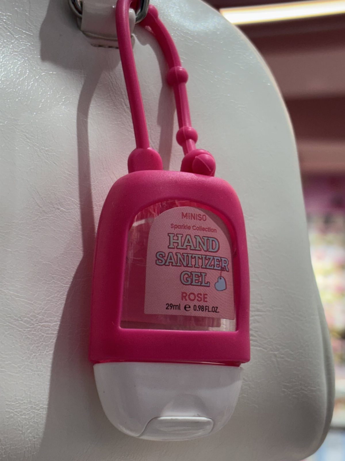 Travel Necessities for Japan: 10 Items Worth Packing 6 Pink hand sanitizer gel bottle hanging from a white textured bag strap.