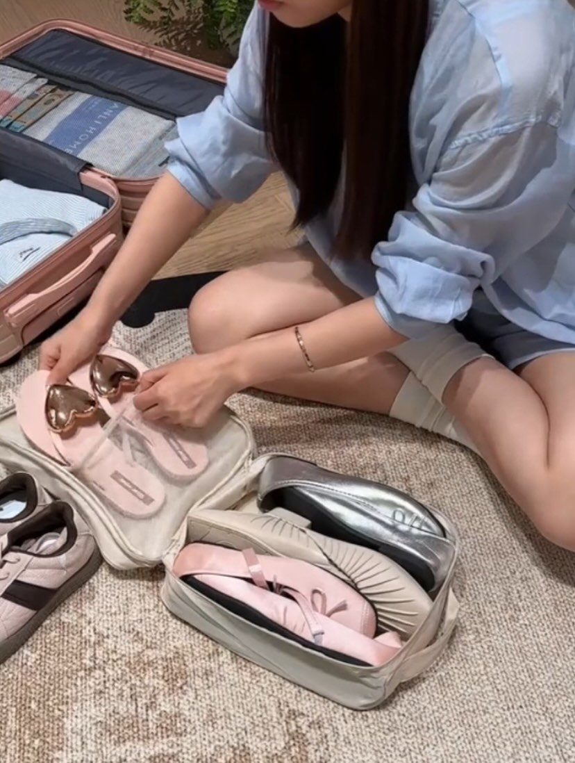 Travel Necessities for Japan: 10 Items Worth Packing 10 Person packing pink and silver shoes into a white fabric organizer bag.