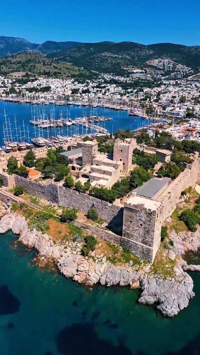 Bodrum Castle stone fortress on a rocky coast overlooking a harbor and town.