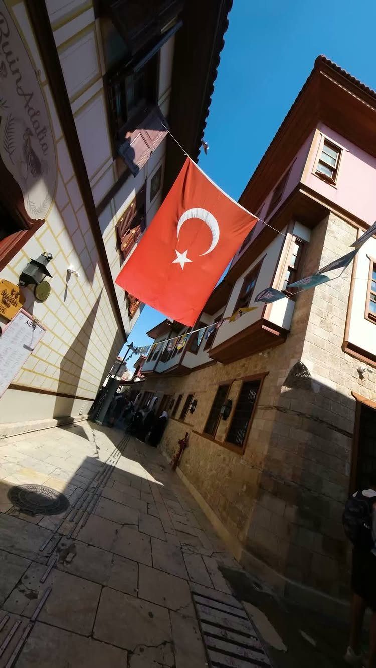 Turkish flag hanging over a narrow cobblestone street with traditional old town buildings.