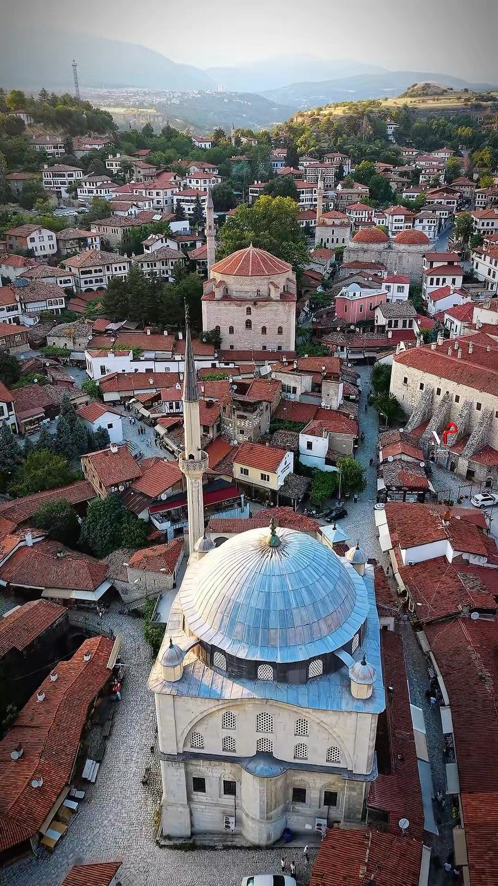 Traditional Ottoman houses with red roofs surrounding a domed mosque in Safranbolu.