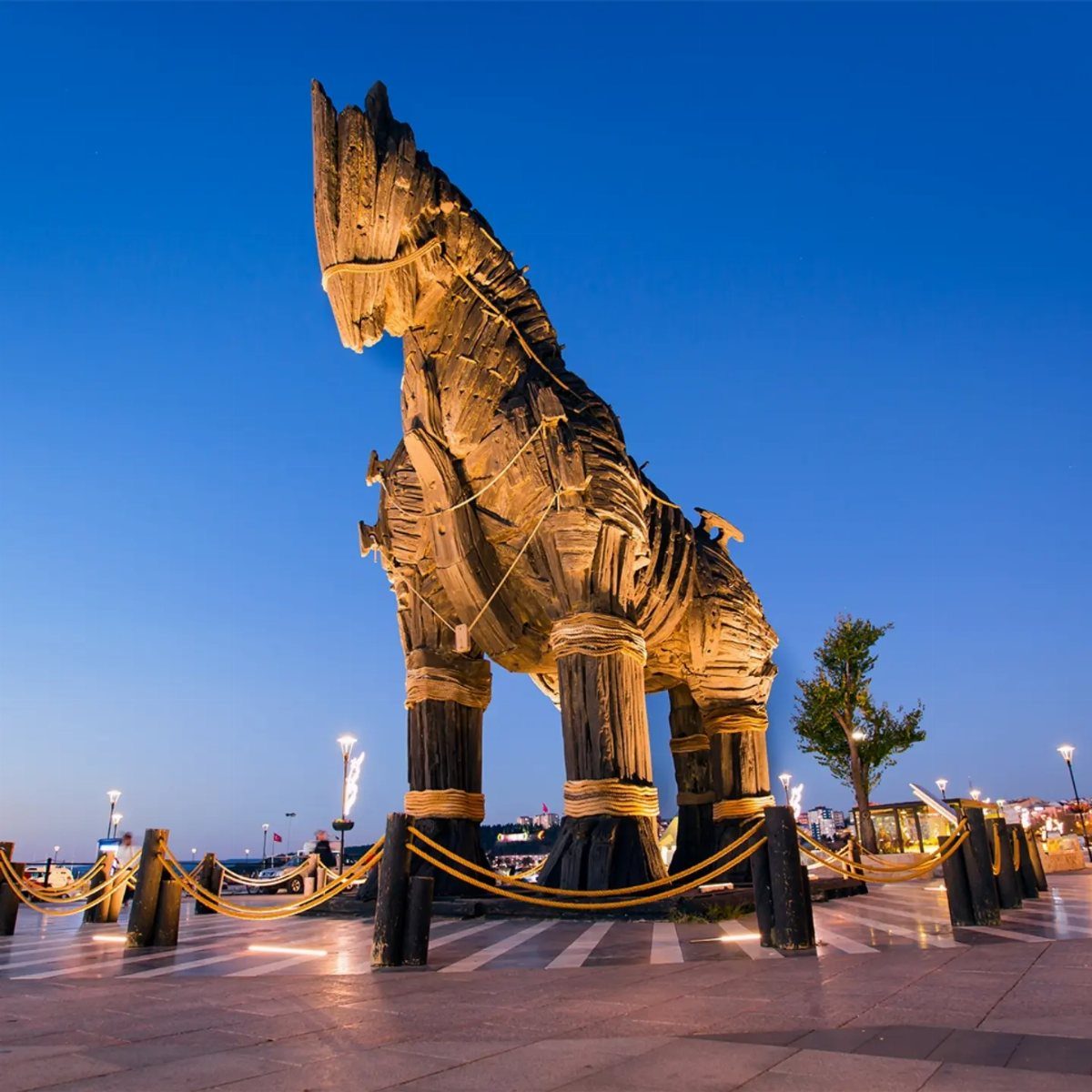 Large wooden Trojan horse statue on a paved plaza under a blue dusk sky.