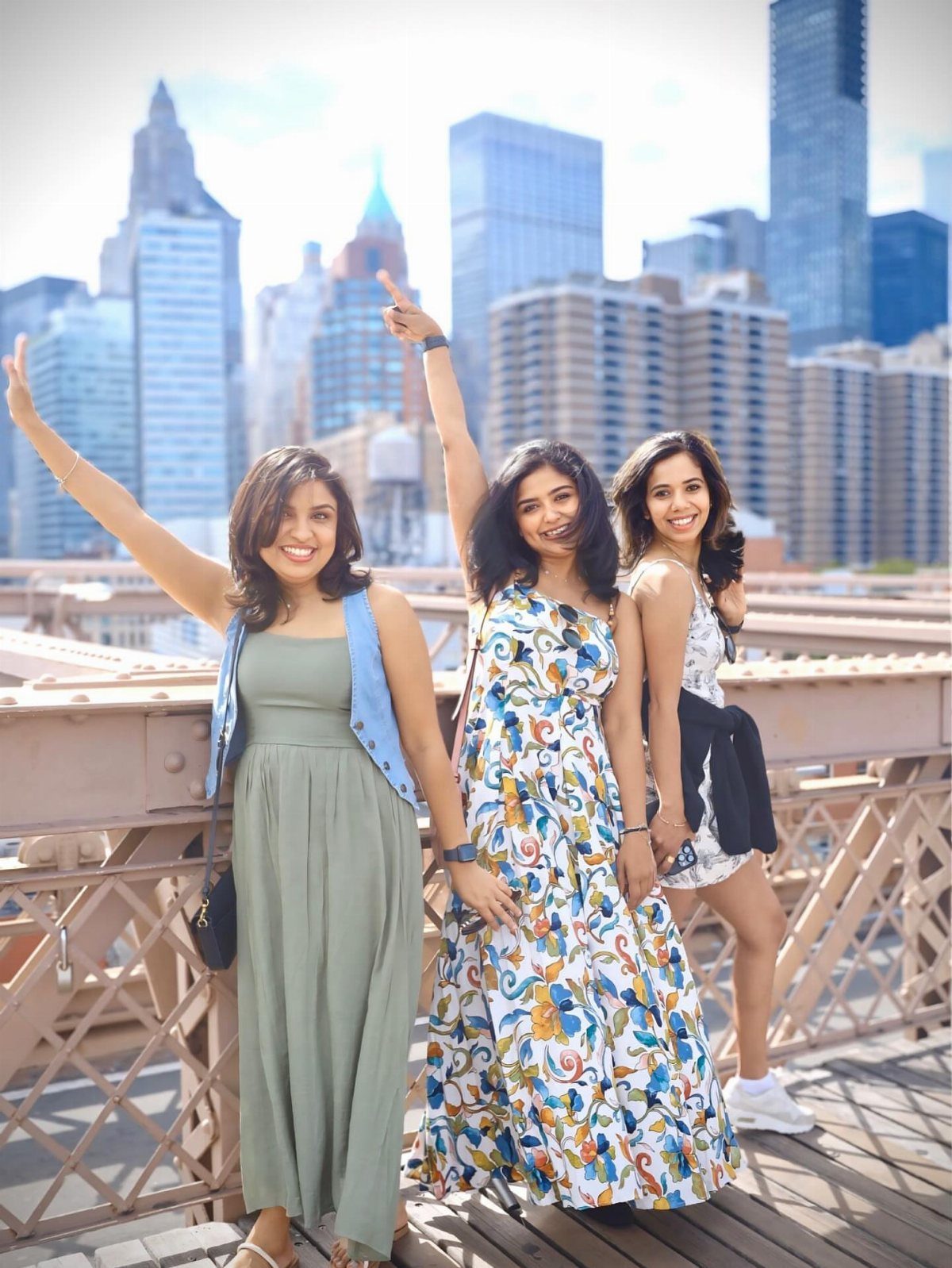 12 Vacation Ideas with Friends, from Cruises to Cancun 10 Three women posing on the Brooklyn Bridge with the New York City skyline behind.