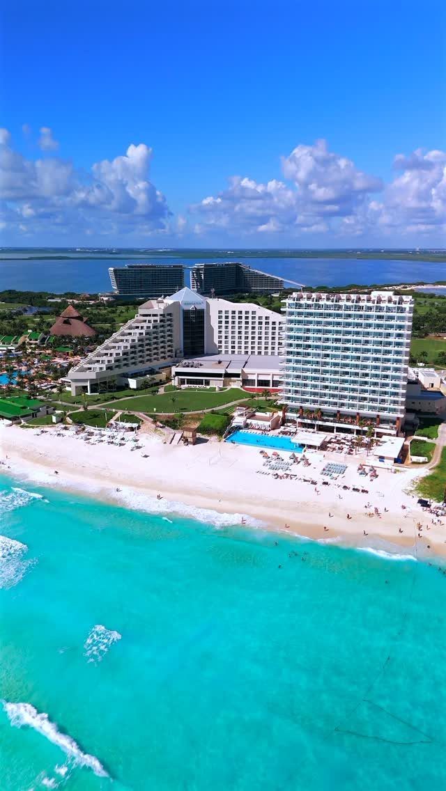 12 Vacation Ideas with Friends, from Cruises to Cancun 3 Beachfront resort with white high-rise buildings on a white sand beach by turquoise water.