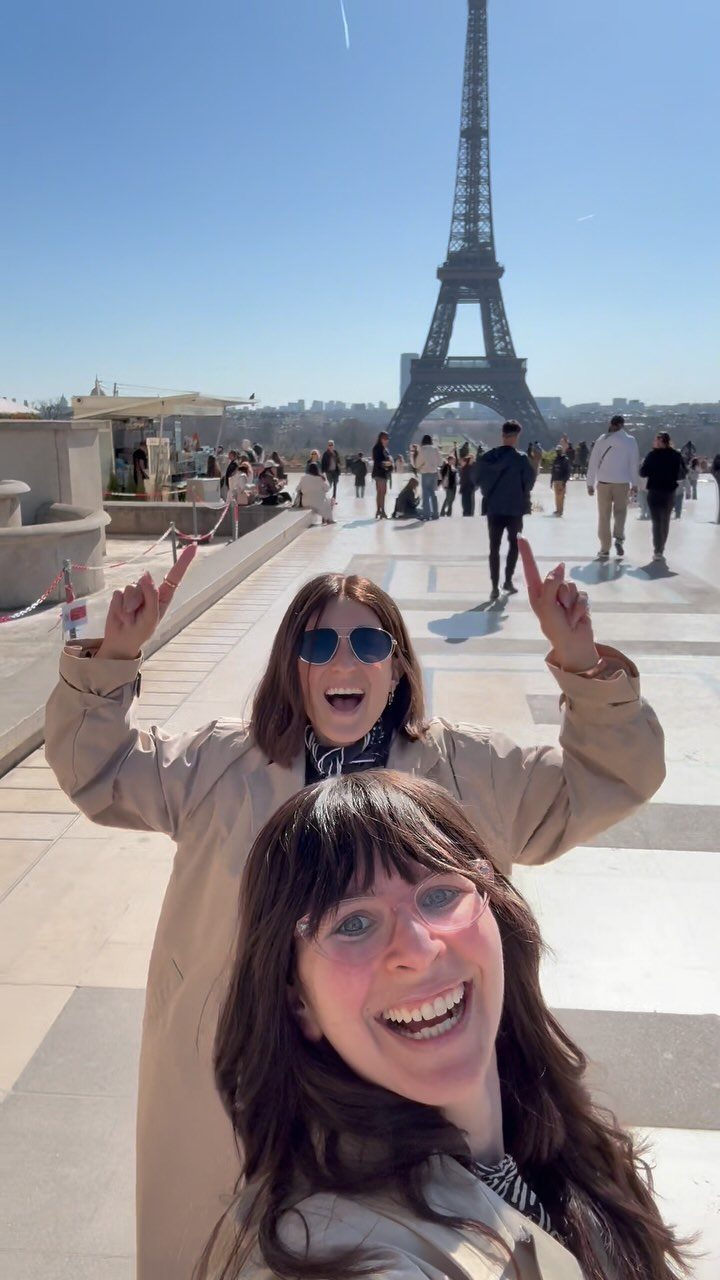 12 Vacation Ideas with Friends, from Cruises to Cancun 8 Two women smiling for a selfie with the Eiffel Tower in the background.
