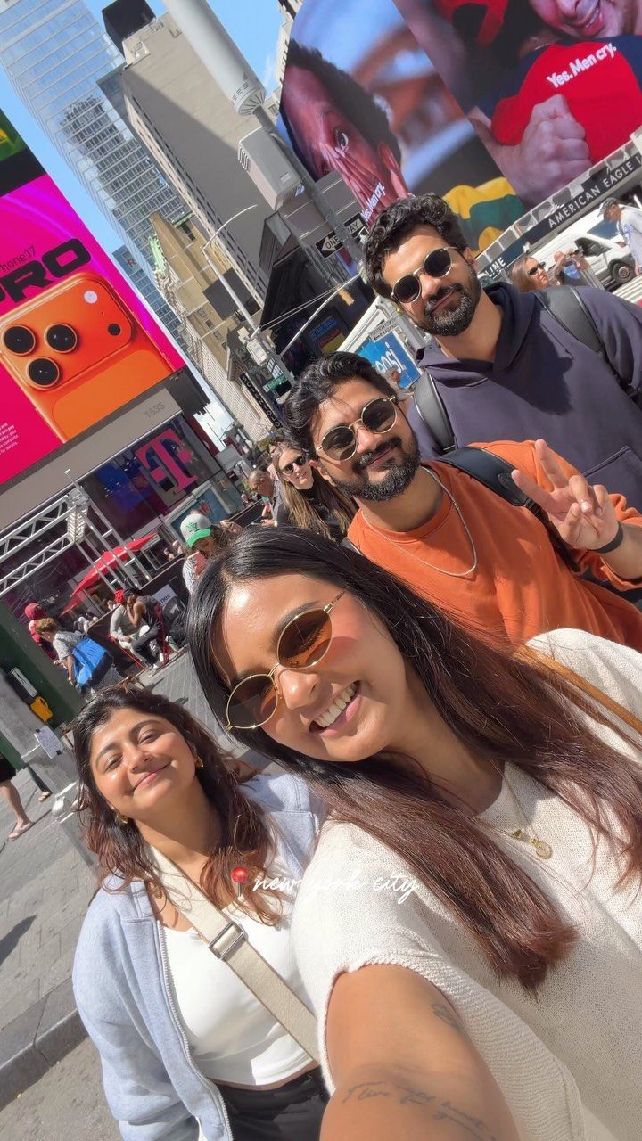 12 Vacation Ideas with Friends, from Cruises to Cancun 11 Four friends smiling for a selfie amidst the bright billboards of Times Square.