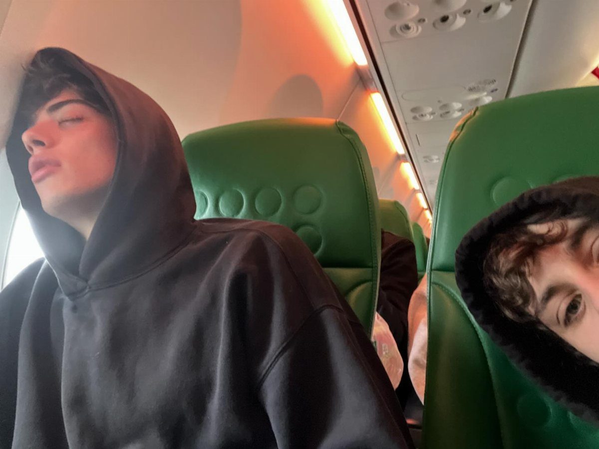 9 Ideas for What to Do on the Plane Besides Scrolling 8 Young man sleeping in a green airplane seat wearing a black hoodie.