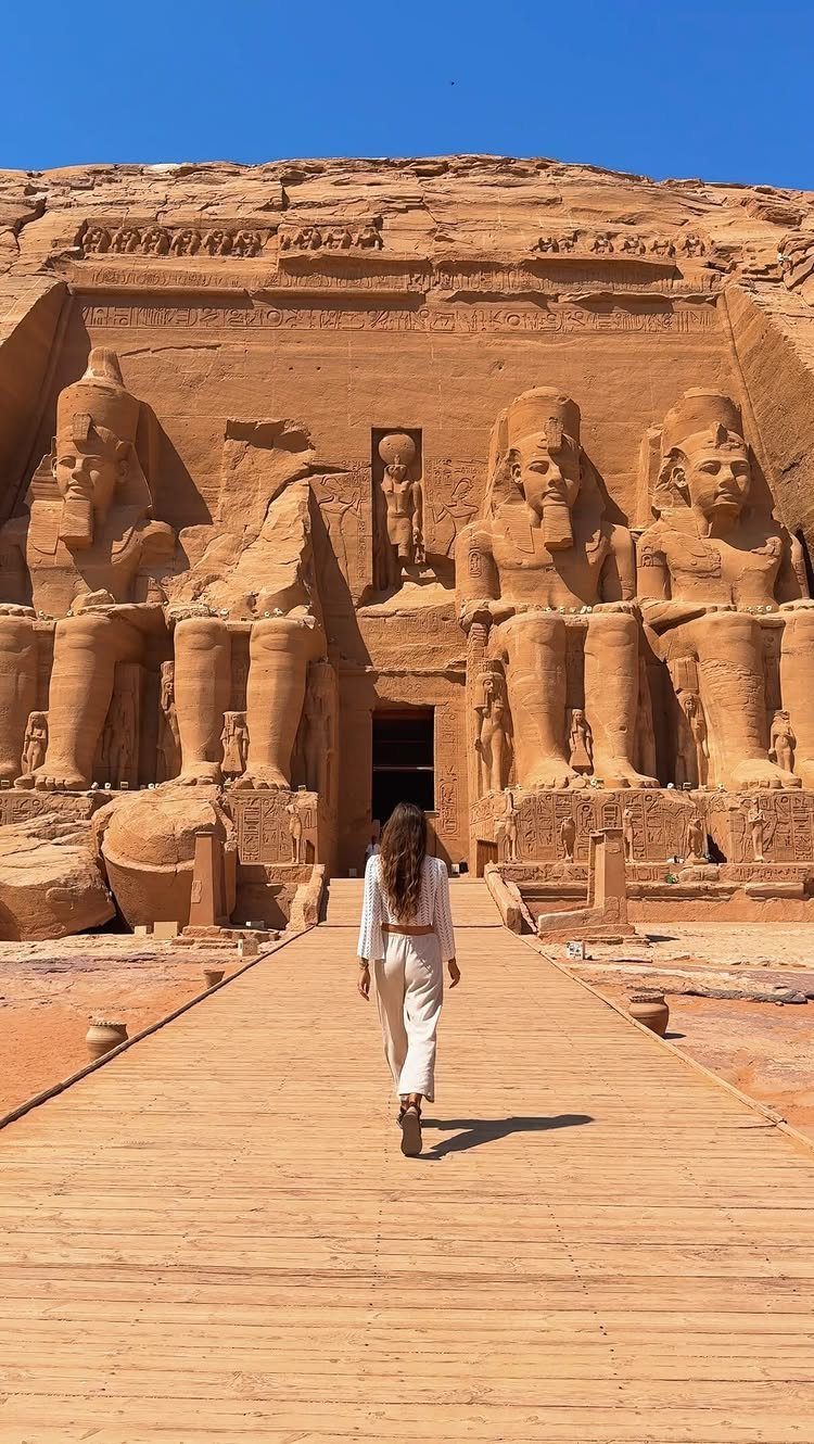 Woman walking toward the giant carved stone statues of Abu Simbel temple
