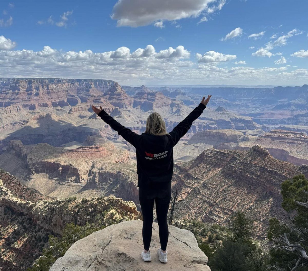 Woman standing on a cliff edge overlooking the vast Grand Canyon landscape