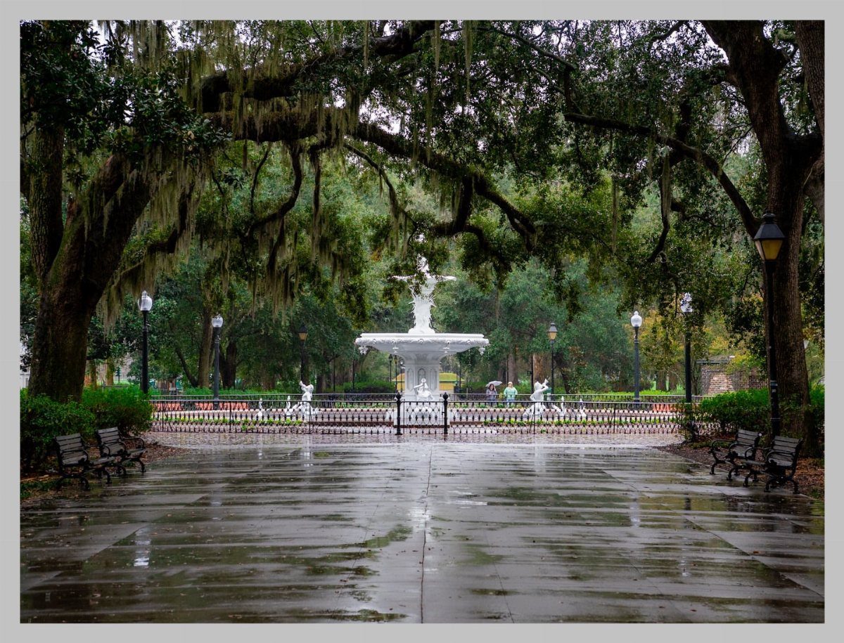 White tiered fountain in a park square surrounded by oak trees with Spanish moss