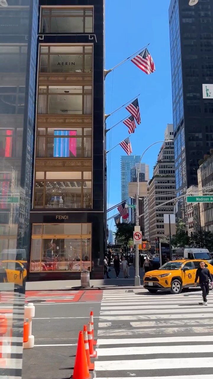 City street with skyscrapers, American flags, and a yellow taxi in New York.