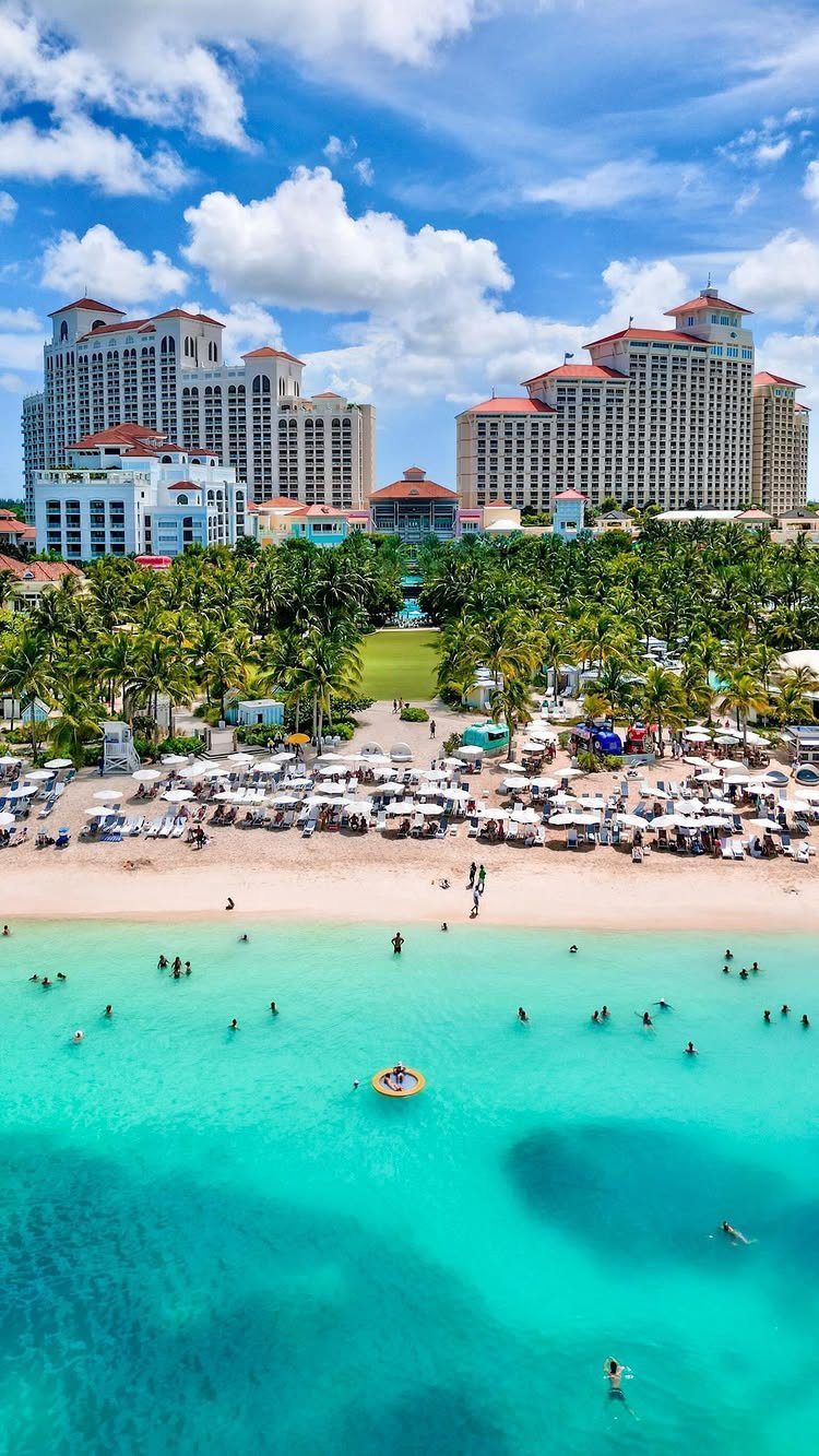 Tropical beach resort with turquoise water, white sand, and large luxury hotels.