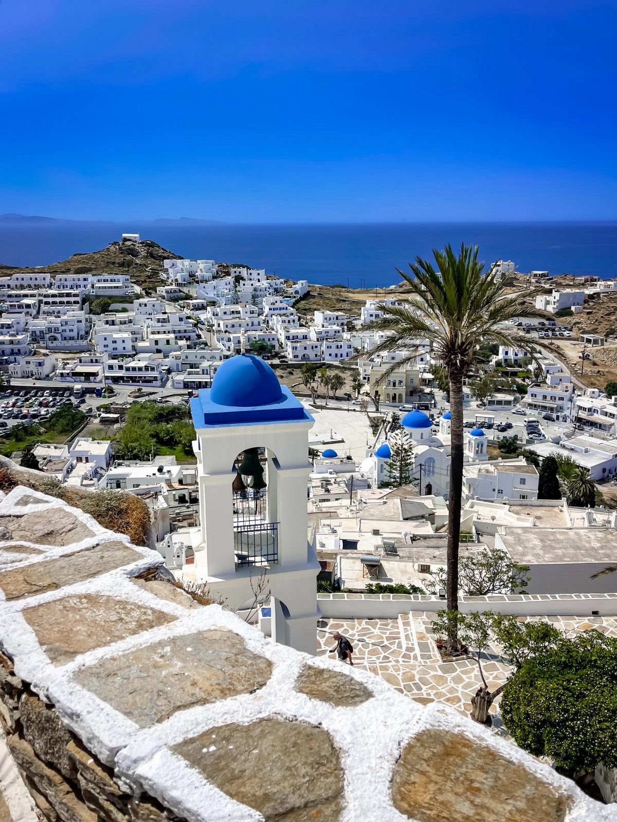 White Greek village with blue-domed churches overlooking the deep blue Mediterranean Sea.