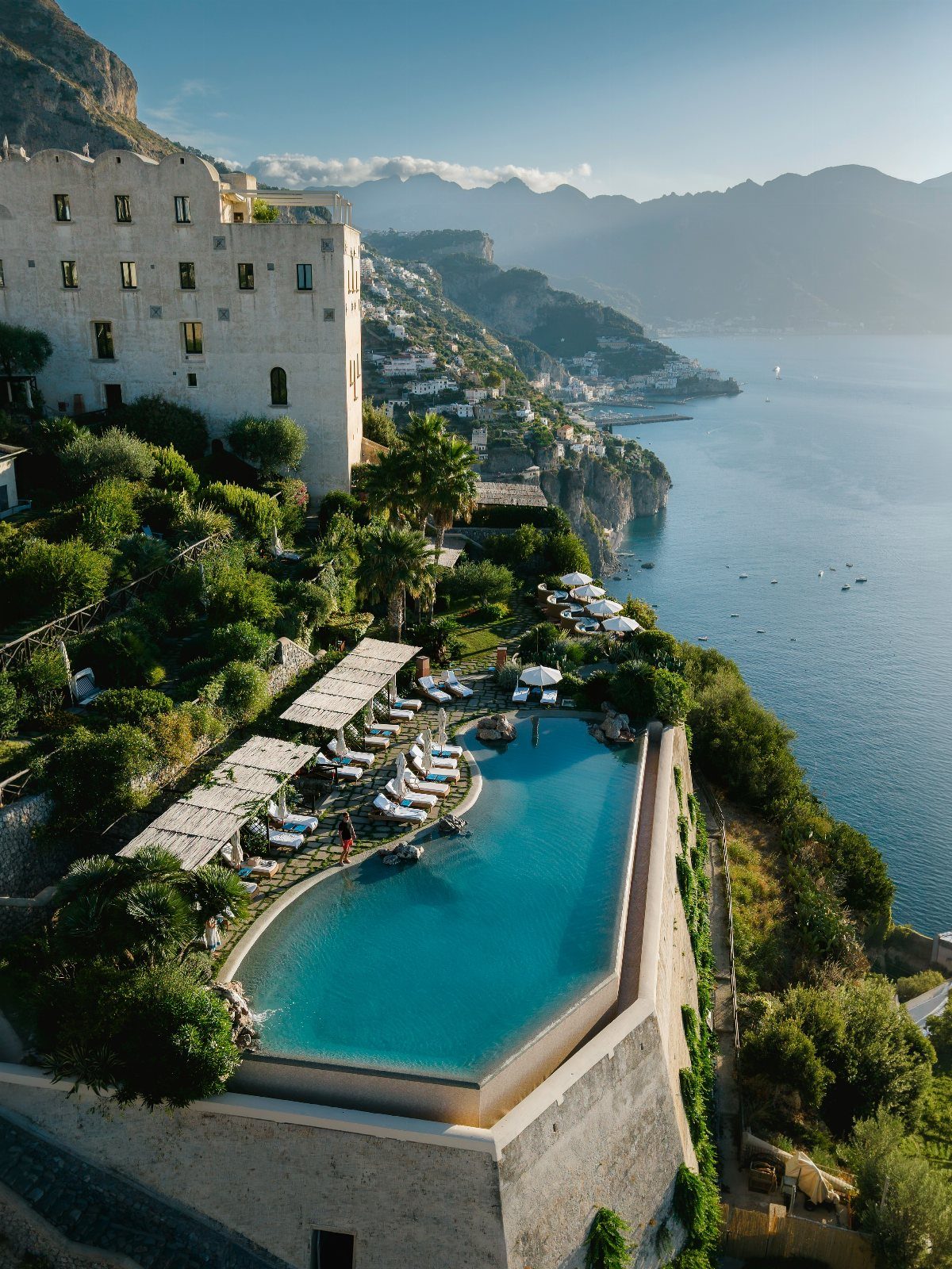 Infinity pool on a cliffside overlooking the Mediterranean coast and distant mountains.