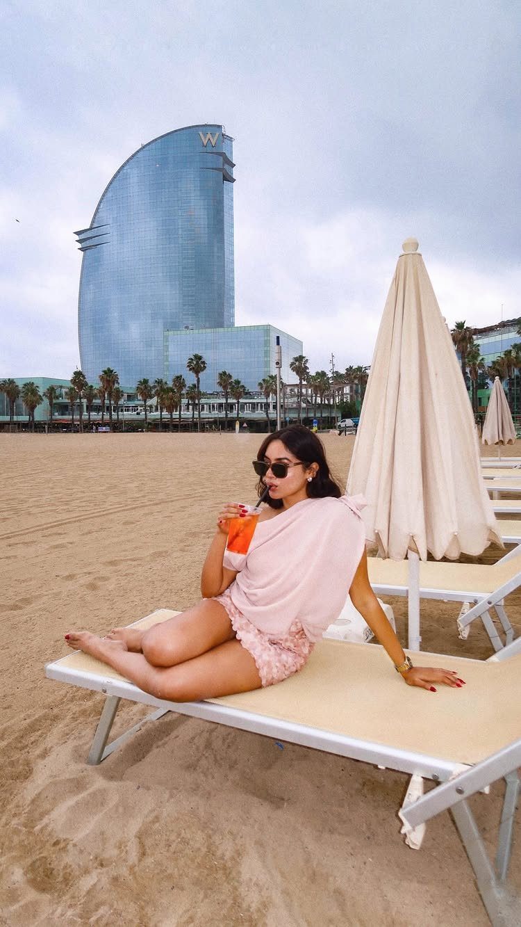 Woman relaxing on a beach lounger with the W Barcelona hotel in background